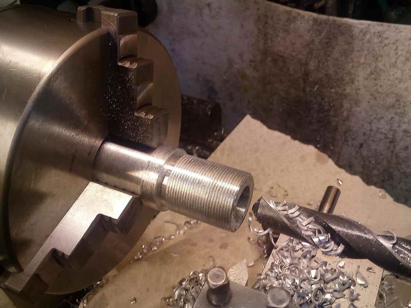 A centre drill entering bar stock held in a lathe chuck